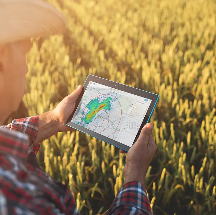Farmer using the CIRRUS weather software displayed on a tablet showing live radar tracking in a field